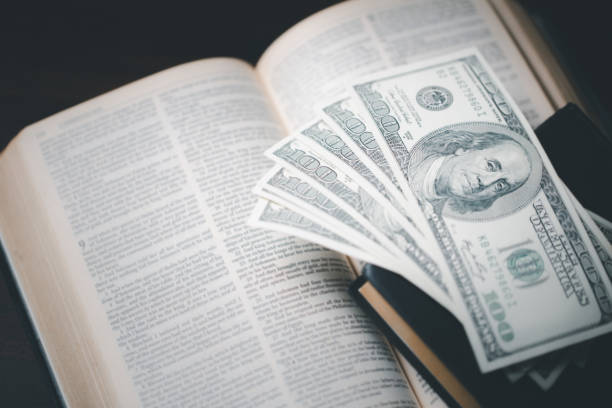 One tenth or tithe is basis on which Bible teaches us to give one tenth of first fruit to God. coins with Holy Bible. Biblical concept of Christian offering, generosity, and giving tithes in church.