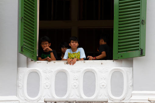Jakarta, Indonesia - November 6, 2010.
The Jakarta History Museum in Fatahillah Square at Kota Tua in Jakarta, Indonesia. It is a popular place for visitors, tourists and local students to visit. Here are four young men looking out of one of the windows.