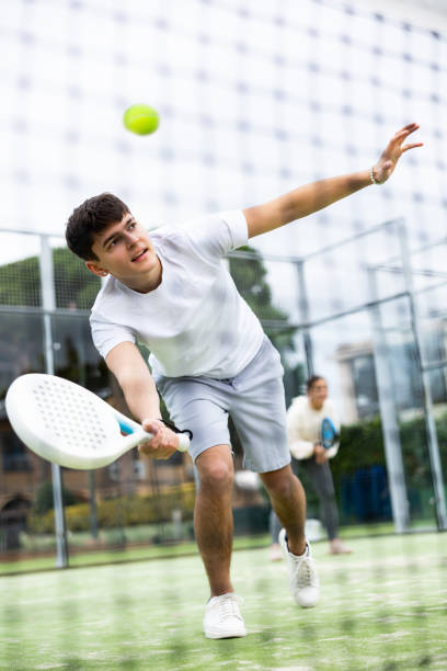 istock Sportive young man playing padel with partner outdoors. View through tennis net 1459206832
