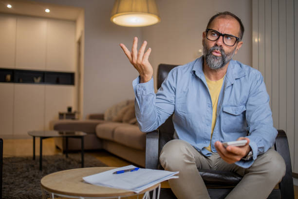 istock Mid adult man using calculator while going through bills and home finances 1459208776