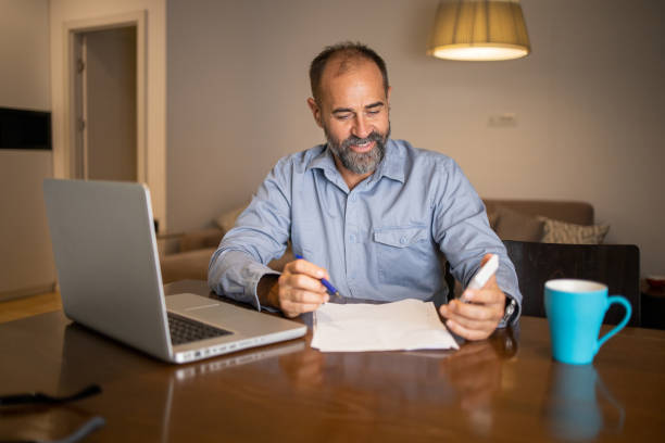 istock Mid adult man using calculator while going through bills and home finances 1459209645