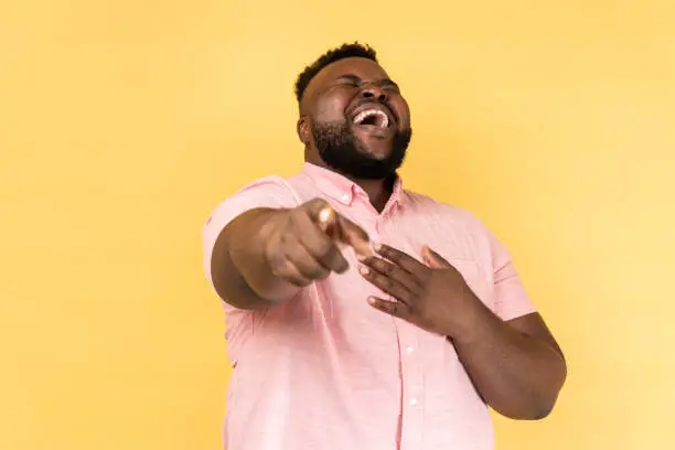 Photo of Man laughing out loud holding belly and pointing finger on you, mockery