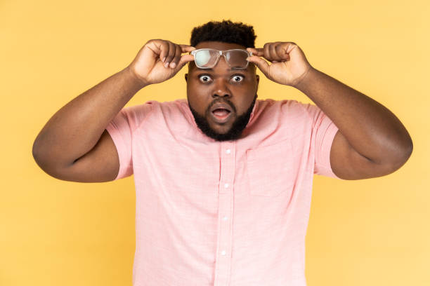 istock Man standing raised his optical glasses and looking at camera with big eyes and open mouth. 1459210810