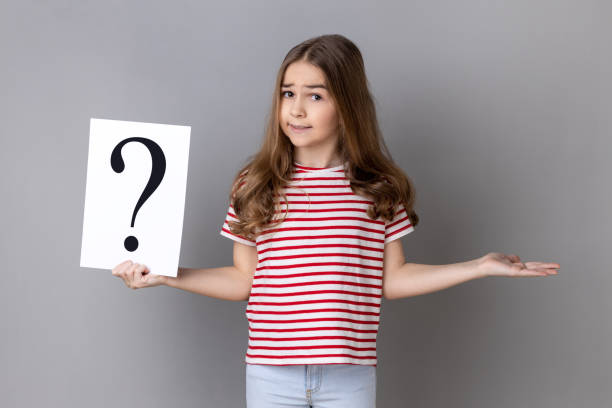 istock Little girl holding paper with question mark, making decision, not sure correct answer. 1459210861