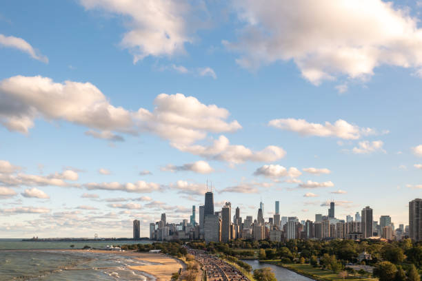 Downtown Chicago city skyline aerial centered over traffic along Lake Shore Drive between South Lagoon and Lake Michigan on a sunny day with fluffy white clouds in a blue sky above. stock photo