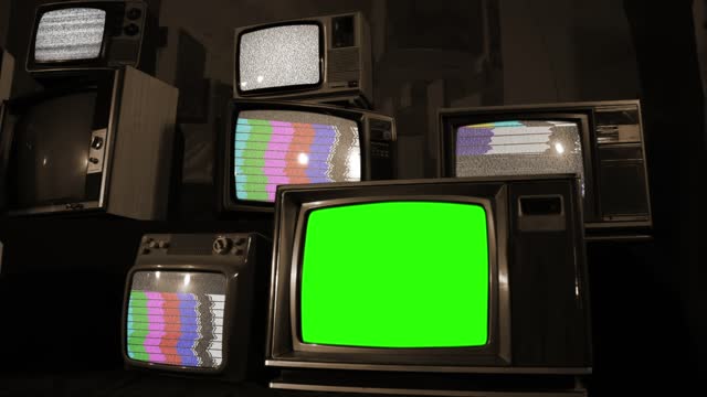 Retro Television with Green Chroma Key Screen Among Piled Retro TVs. Sepia Tone.