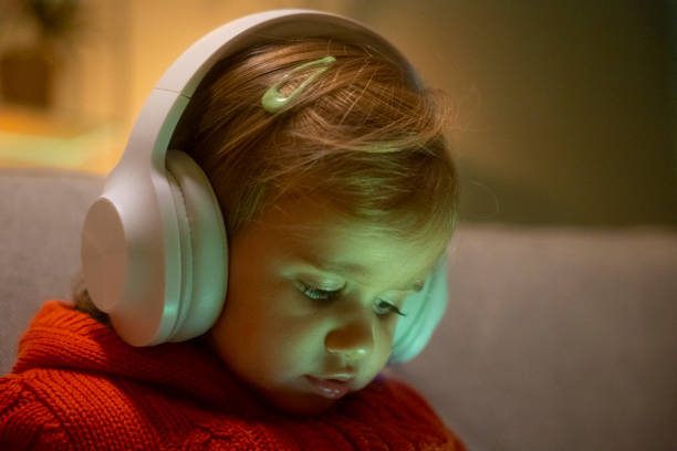 Kid uses phone and headphones to watch TV. Happy childhood. Family time at home. screen time and technology in babies stock pictures, royalty-free photos & images