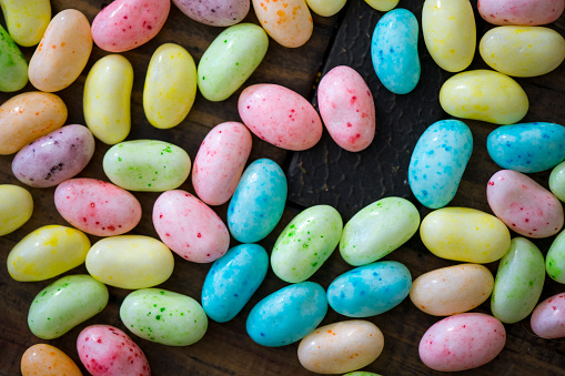 Closeup of bright, pastel colored, speckled Easter candy on a wooden table.