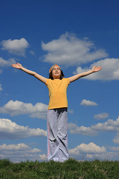 istock Girl holding hands up against blue sky 145922004