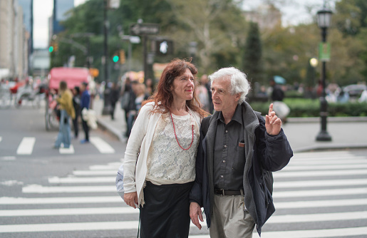 Cheerful, senior couple crossing the street together and talking in Manhattan, New York.