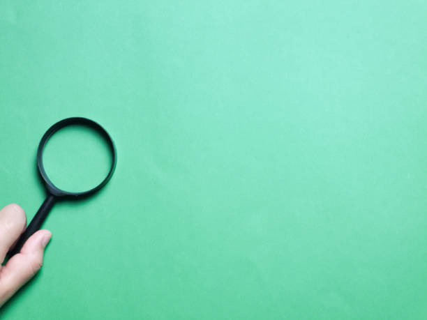 istock Top view image image hand holding magnifying glass against green background. 1459222029