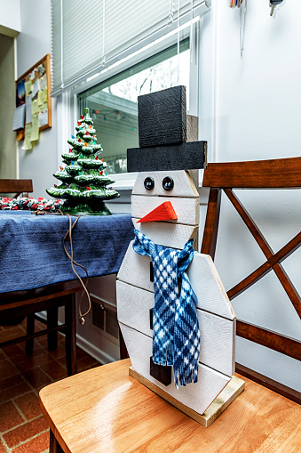 After the holiday season is over, some household outdoor decorations - including a flat wooden snowman rocking a blue plaid scarf, and a dark green porcelain Christmas tree decorated with colorful Christmas lights - are waiting in the kitchen of a residential home waiting to be taken down to the basement for storage.