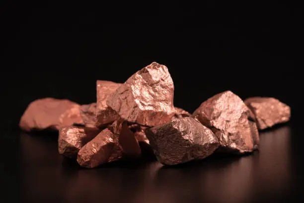 Photo of Ingots of pure copper or pink gold on a black background.