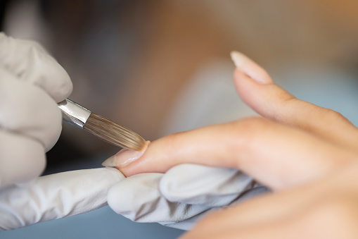 Manicurist applying acrylic on nails