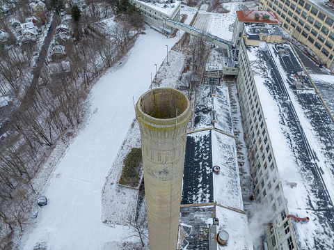Winter aerial drone photo of an abandoned industrial concrete smoke stack.