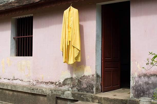 A yellow buddhist ca sa hanging behind temple walls. Image taken in Vietnam.