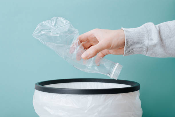 istock Person hand throwing crumpled plastic bottle into trash can, close-up 1459252511
