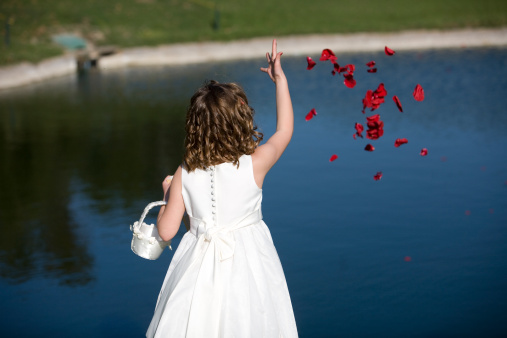 Girl from wedding throwing flowers into a lake