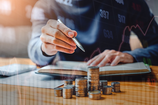 Graph on rows of coins for finance and banking on digital stock market financial exchange and Trading graph Double exposure city on the background