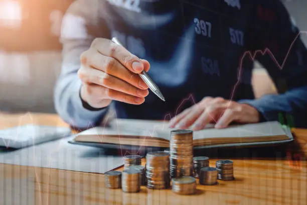 Photo of Graph on rows of coins for finance and banking on digital stock market financial exchange and Trading graph Double exposure city on the background