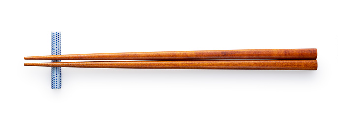 Wooden chopsticks and chopstick rests placed on a white background. Viewed from above.