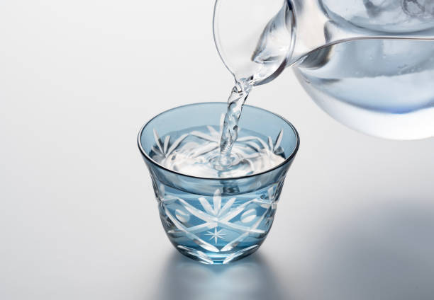 Sake poured into a faceted glass on a white background. Sake poured into a faceted glass on a white background. The image of sake. The moment of pouring. saki photos stock pictures, royalty-free photos & images