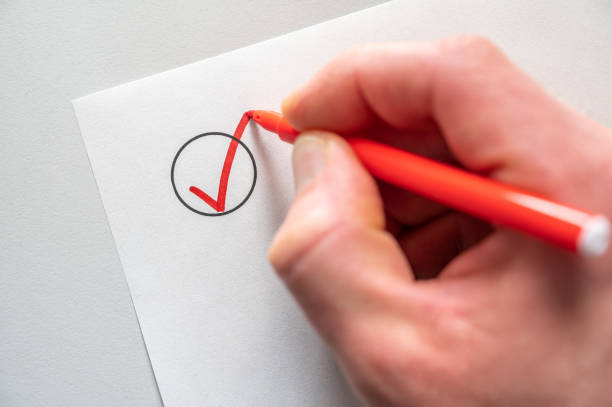 istock Checking off a list with red pen against a white background with text space 1459262886