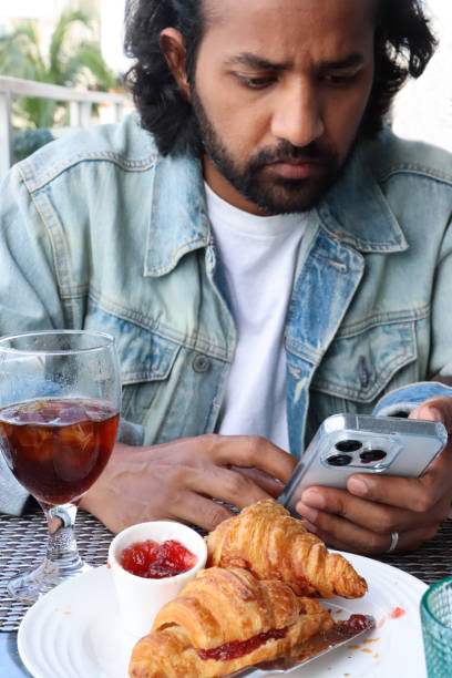 Stock photo showing a close-up view of a meal with two golden brown croissants, french pastry treats served with strawberry jelly preserve in a white bowl, a delicious breakfast brunch.
