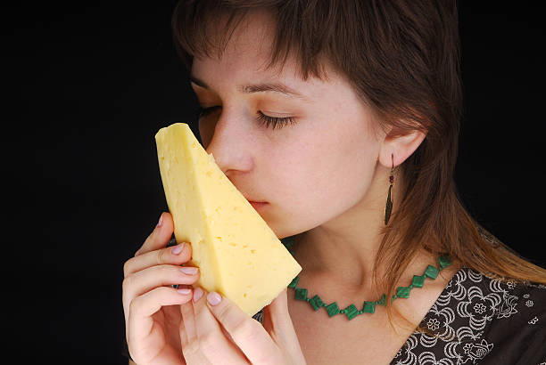 Beautiful woman smells piece of cheese stock photo