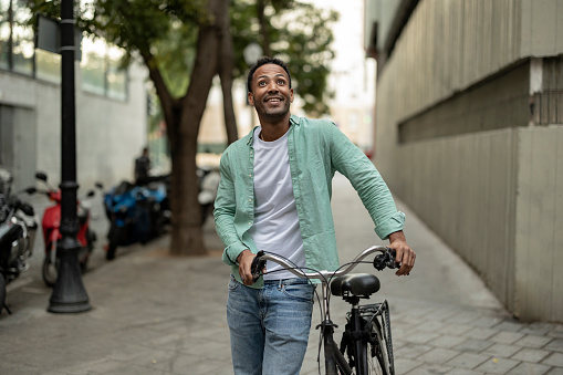 handsome african man tourist backpacker in the city with rented bike