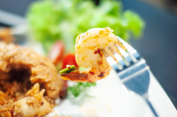 Tom Yum Kung Thai spicy chilly paste fried rice with fork stick into shrimps and green salad and tomato side dish  copy space photography