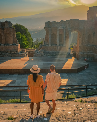 Taormina Sicily, couple watching the sunset at the Ruins of the Ancient Greek Theater in Taormina, Sicily. couple mid age on vacation Sicilia