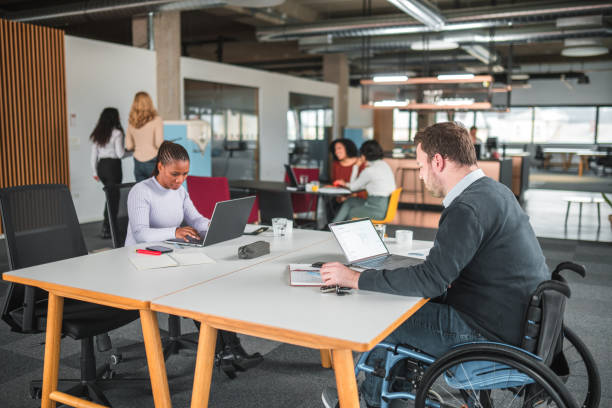 istock Shared Co-Working Desk With Female and Disabled Male Entrepreneur Working 1459274415