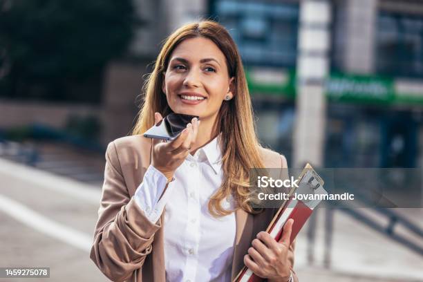 Corporate Woman Records Voice Message On Smartphone Talks Into Microphone On Mobile Phone Stock Photo - Download Image Now