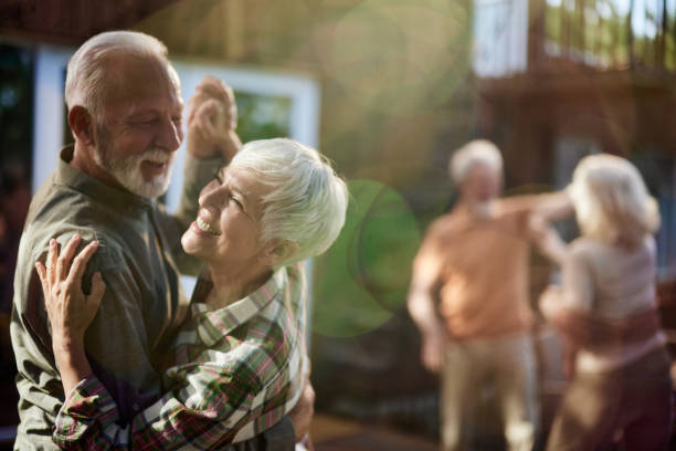 coppia anziana felice che balla durante una festa su una terrazza. - holding hands couple senior couple togetherness foto e immagini stock