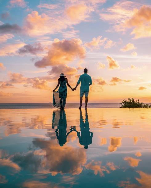 coppia che guarda il tramonto alla piscina a sfioro santa lucia, coppia in vacanza tropicale isola di st lucia - infinity pool foto e immagini stock