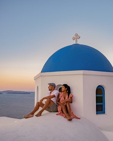 A couple on vacation in Santorini Greece, two men and women visit Oia Santorini with whitewashed buildings. in Santorini Greece