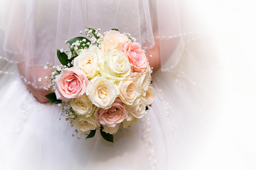 Wedding bouquet with daisies and roses held by a bride.