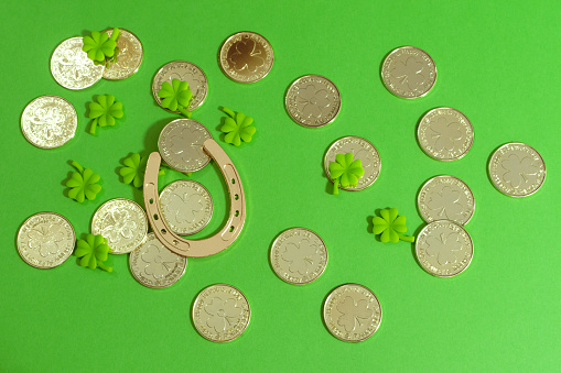 Golden horseshoe, gold coins and clover leaves on green boards. St. Patrick's day holiday symbol.