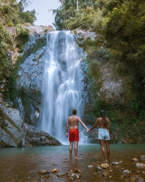casal caminhando para a cachoeira na tailândia, chumphon klongphrao cachoeira tailândia - chumphon - fotografias e filmes do acervo