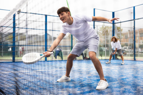 istock View through tennis net of guy padel player hitting ball 1459279945