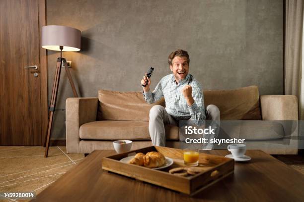 Cheerful Man Celebrating While Watching A Sports Game On Tv Stock Photo - Download Image Now