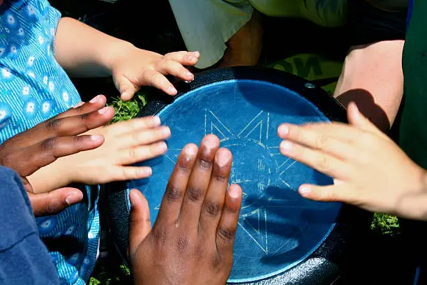 A group of children drum together on a blue,  aluminum drum.