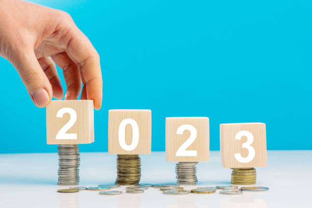 istock Hand place wooden cube 2023 with stack of coins with blue background and copy space. Saving money and financial plan concept for investment in new year 2023. 1459280606