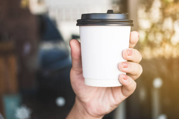 istock hand holding takeaway paper coffee cup on  morning sunlight. 1459281680