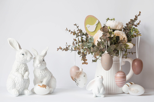 A beautiful postcard. Banner. The concept of a bright Easter holiday. Bouquet of flowers, white rabbits and Easter eggs on a white isolated background.