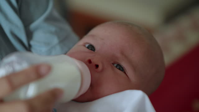 Mother giving bottle of milk to her little newborn baby