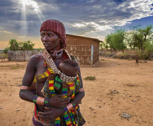 frau aus dem stamm der hamar (buchstabiert hamer), die ihr baby trägt, omo river valley im südwesten äthiopiens. - hamer woman stock-fotos und bilder
