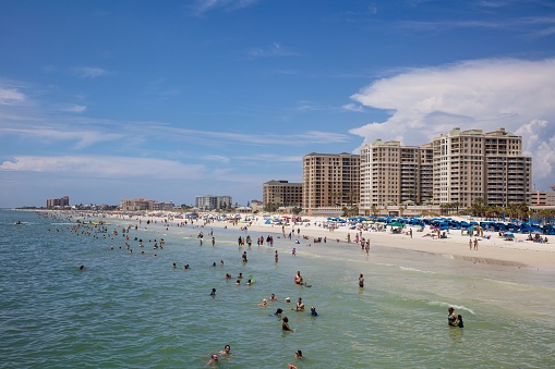 Clearwater, United States – May 19, 2022: A picturesque view of the Clearwater beach with people swimming in the water and resting on the beach, Florida