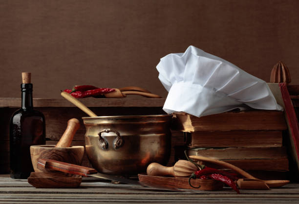 istock Chef's hat, vintage cookbooks, and old kitchen utensils on the kitchen table. 1459286703